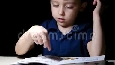 小孩用<strong>手指</strong>指着家里书中的图画，晚上他坐在一张<strong>灯</strong>点亮的桌子旁